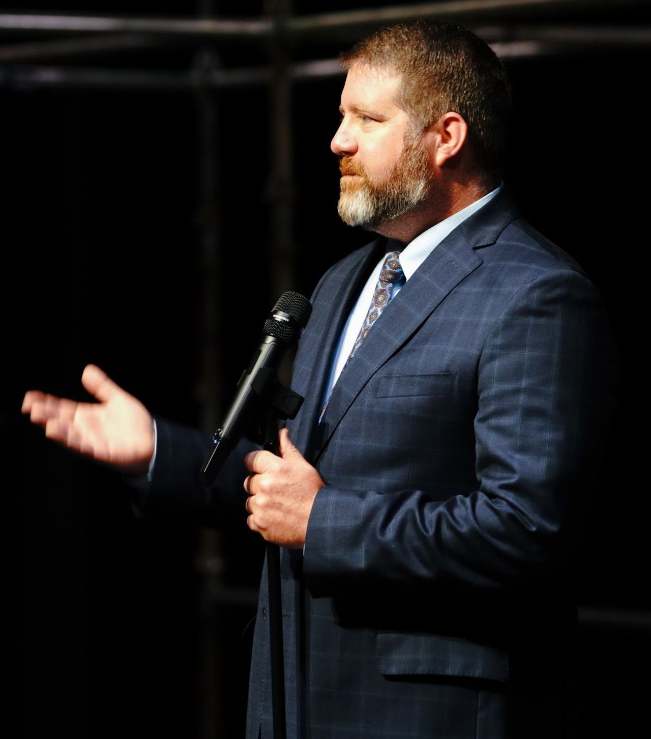 Dr. Lane Freeman speaking into a handheld microphone and gesturing toward the audience.